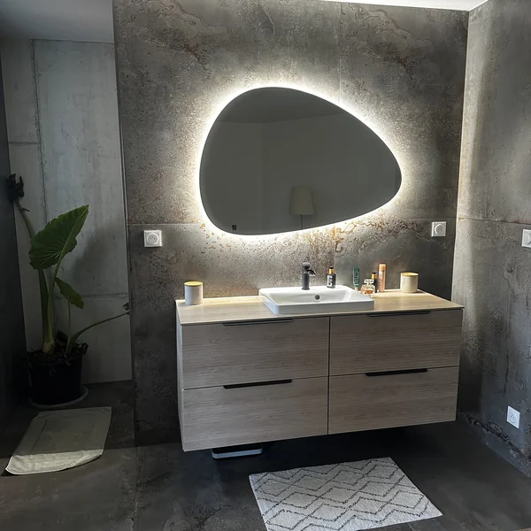 Salle de bain avec mur grand format effet pierre oxydée et meuble vasque bois