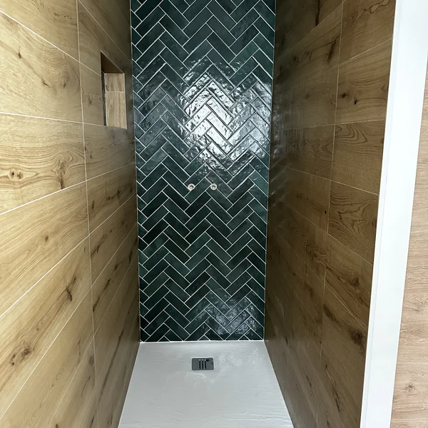 Douche avec mur en zellige vert posé en chevrons et faïence effet bois
