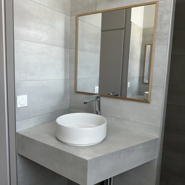 Vasque ronde sur plan carrelé effet béton avec miroir cadre bois