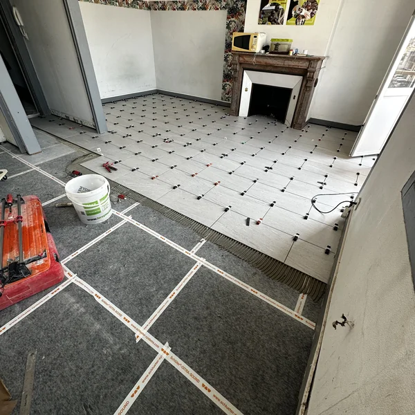 Pose de carrelage de sol en cours avec natte de désolidarisation Schlüter